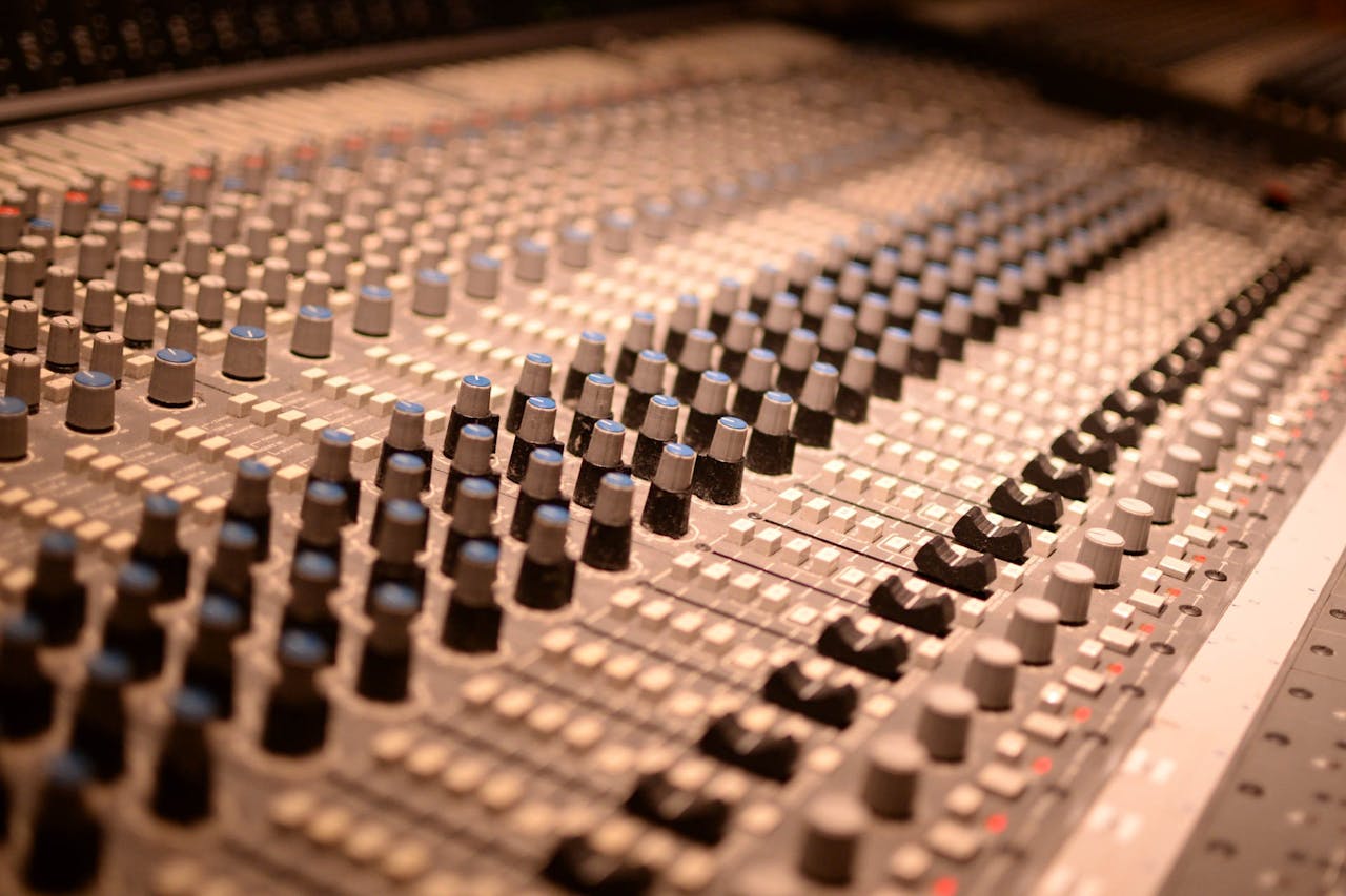 services-03 Detailed view of an analog audio mixing console with various knobs and sliders in a sound studio.