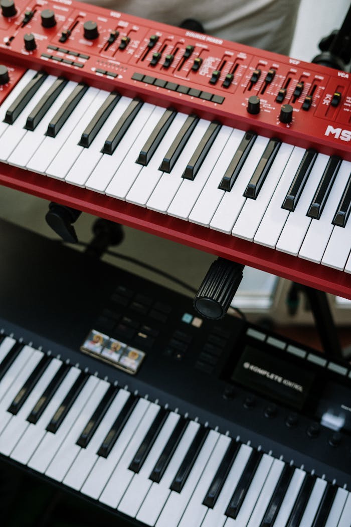 gallery-03 Vertical shot of red and black electronic keyboards in a home studio setting.